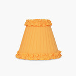 Handcrafted rattan cordless lamp with a vibrant orange pleated lampshade and ruffled edges.