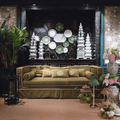 Stylish living room featuring an olive green sofa with monogrammed pillows and an elegant backdrop of decorative plates.